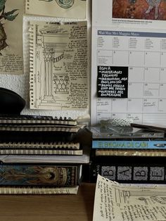 many books are stacked on top of each other in front of a wall with pictures