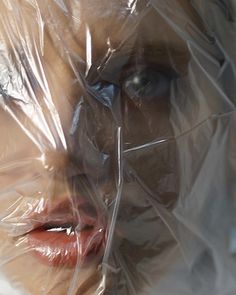 a woman's face is wrapped in plastic and has her eyes partially hidden behind the plastic