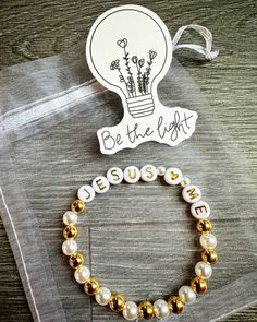 a bracelet that says be the light with some beads on it and a sticker