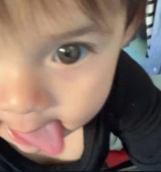 a young child making a funny face with his tongue hanging out and looking at the camera