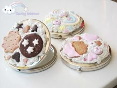 three decorated cookies sitting on top of a white table next to other desserts and pastries