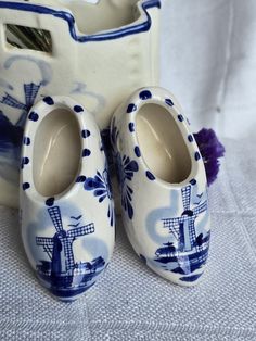 two blue and white ceramic shoes next to a vase