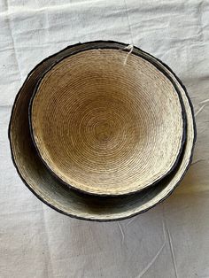 two black and white bowls sitting on top of a cloth covered tablecloth, one is empty