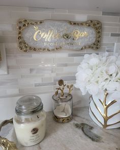 there are some flowers and candles on the counter in this bathroom sink area that is decorated with gold accents