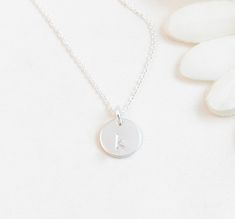 "Minimal Sterling Silver Initial Charm Personalized Necklace: Perfect for layering or alone. All components are sterling silver. One letter of your choice will be hand stamped onto the small disc - choose from 4 fonts. This is a subtle, unoxidized letter with a minimal look. The initial charm is of high quality thickness and 3/8\" in diameter. Available in size 14\" (choker length on most adults), 16\", or 18\" (shown on model). Arrives on a necklace card tucked into an organza gift pouch - read Simple Silver Initials Charm Necklace, Silver Minimalist Personalized Initial Necklace, Silver Simple Charm Necklaces With Initials, Simple Silver Charm Necklaces With Initials, Silver Minimalist Hand Stamped Necklace, Dainty Sterling Silver Round Disc Initial Necklace, Simple Sterling Silver Initial Necklace For Anniversary, Dainty Sterling Silver Round Disc Charm Necklace, Personalized Minimalist Sterling Silver Charm Necklaces