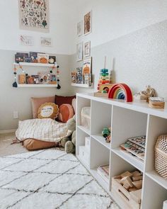 a child's room with white shelving and toys on the floor, including a teddy bear