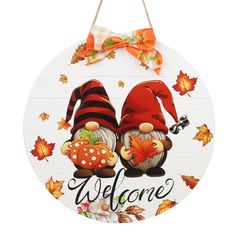 a welcome sign with two gnomes on it and autumn leaves around the sign that says, welcome