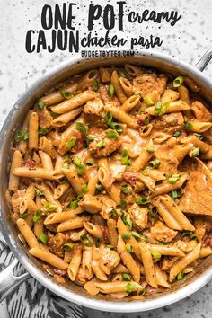 a skillet filled with pasta and meat covered in sauce on a marble counter top