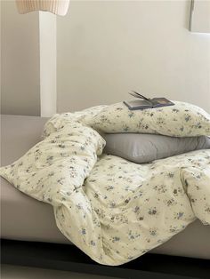 a bed with two pillows on top of it and a book sitting on the pillow