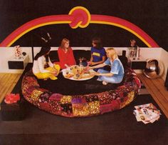 three women sitting on a bed with food and drinks in front of an arch shaped like a rainbow