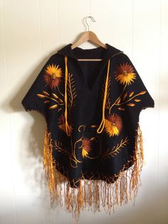 "Mexican folk embroidered poncho / cape / serape. Stunning. Deep black wool with vivid gold and copper embroidery. Collar with gold fabric beneath. Detailed embroidery on front and back. Beautiful hem fringe and long, gold cord at neck The condition is clean and rustic. No holes, wear or split seams. There are a few, expected pulls in the vintage embroidery hand work. Approximate Measurements: No tags. Underarm to underarm-29\" Sleeve length- 15\" - Short sleeve measured from hem of sleeve to ed Fall Folk Embroidered Poncho, Winter Festival Embroidered Poncho, Traditional Embroidered Poncho For Winter, Traditional Embroidered Winter Poncho, Embroidered Long Sleeve Fall Poncho, Fall Long Sleeve Embroidered Poncho, Festival Black Embroidered Poncho, Bohemian Black Poncho For Fall, Traditional Fall Poncho With Fringe