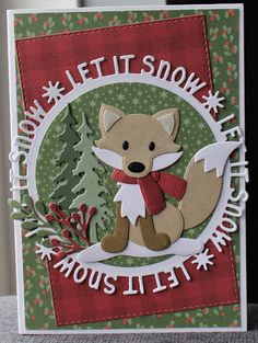 a handmade christmas card with a fox and snowflakes in the background, on top of a table