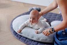 a baby sitting on a pillow being held by a woman