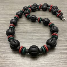 This bold long necklace is made of 20mm black large chunky fluted wooden beads with red, black, green ceramic rondelle beads and 8mm black lava stone beads. It has a stainless steel lobster claw style clasp with stainless steel wire guards. Available in lengths of 28 and 30 inches. Prices vary. Artisan Black Beads 8mm, Artisan Black 8mm Beads, Artisan Black Necklaces With 8mm Beads, Black Wooden Beads For Jewelry Making, Black Lava Stone Round Bead Necklaces, Artisan Black Necklace With 8mm Beads, Artisan Black Necklace With Round Beads, Artisan Black Round Bead Jewelry, Artisan Black Round Beads Jewelry