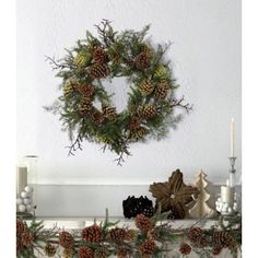 a wreath is hanging on the mantle with pine cones