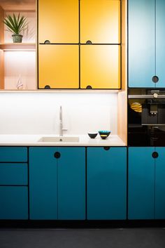 a kitchen with blue cabinets and yellow cupboards on the wall, along with a white counter top