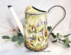 a vase with flowers painted on it next to a toothbrush holder and flower arrangement