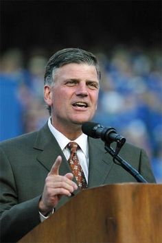 a man giving a speech in front of a crowd at a football game with his hand up