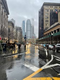 people crossing the street on a rainy day in new york city, with skyscrapers in the background