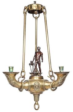 a brass chandelier with two candles and a figurine on the bottom