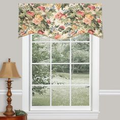 a window with a flowered valance hanging from it's side and a lamp next to it