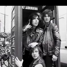 three people are standing in a phone booth