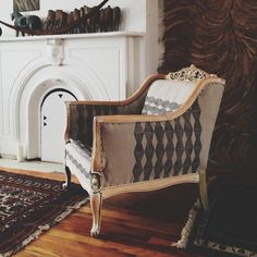 a chair sitting in front of a fire place next to a rug on top of a hard wood floor