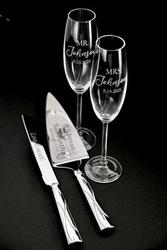 two wine glasses and a silverware set on a black surface with the words mr and mrs engraved on them