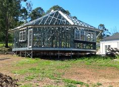 a house that is being built in the middle of some dirt and grass with trees around it