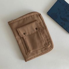 a wallet sitting on top of a white table next to a blue book and pen