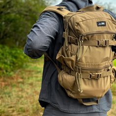 a man with a backpack on his back is walking in the grass and looking at something