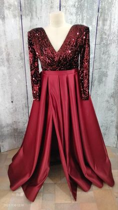 a red dress with sequins on the back and long sleeves, sitting on a mannequin