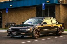 a black car parked in front of a parking lot next to a blue and brown building