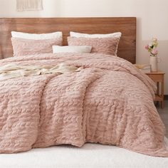 a bed with a pink comforter and pillows