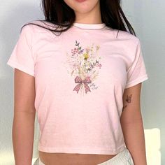 Elevate your summer wardrobe with our Coquette Wildflower Baby Tee! This trendy womens floral bow crop top combines Y2K aesthetic with a modern twist, making it the perfect addition to your closet. Whether you're hitting the beach or strolling through the city, this cute gen Z shirt is sure to turn heads and make a stylish statement. It also makes a great gift for any fashionable teenage girl in your life. Embrace the flower power and bring some fun and flirty vibes to your outfit rotation with Outfit Rotation, Crop Top Y2k, Bow Crop Tops, Aesthetic Shirt, Aesthetic Shirts, Gen Z, Y2k Aesthetic, Baby Tee