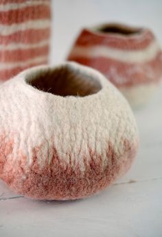 two pink and white vases sitting next to each other on top of a table