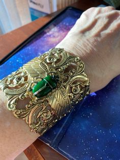 "Egyptian scarab green scarab cuff Wide cuff 2-1/2 inches, scroll pierced antique gold plating over brass.  Open in back for ease of wearing. Winged layered scarab wings with large resin and crystal detailed dark emerald green scarab. Adjustable size 7,8,9 Rich vintage patina Lucky beetle. Speaks life. This is a show stopper. Gorgeous! Limited edition. \"Angelina Verbuni Designs\" Made in USA MyElegantThings" Elegant Green Metal Cuff Bracelet, Handmade Green Cuff Bracelet For Formal Occasions, Antique Gold Cuff Jewelry, Arcane Jewelry, Gold And Emerald Jewelry, Scarab Wings, Egyptian Design Pattern, Dark Beauty Fashion, Egyptian Accessories