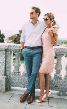 a man and woman standing next to each other on a bridge with their arms around each other