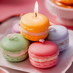 there are four macaroons on the plate with a candle in the middle one