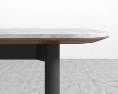 a white marble table with black metal legs and a wooden top on a gray floor