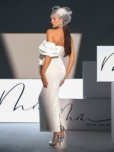 a woman is walking down the runway in a white dress