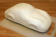 a white car sitting on top of a hard wood floor next to a black object