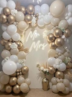 an arch made out of white and gold balloons with the words mr and mrs on it