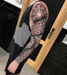 a man with a full sleeve tattoo on his arm and shoulder is standing in front of a door