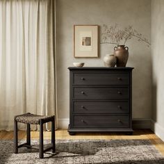 a black dresser with two vases sitting on top of it next to a window