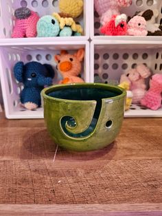 a green ceramic bowl sitting on top of a wooden table next to small stuffed animals