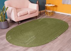 a living room with a green rug on the floor next to a chair and potted plant