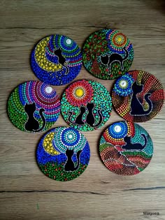 six colorful painted coasters sitting on top of a wooden table