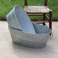 two metal buckets sitting on the ground next to a chair