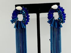 Make a bold statement with these dazzling blue crystal tassel earrings, featuring intricate floral accents and cascading chains. The vibrant blue crystals add a touch of elegance and glamour, while the unique design captures the essence of contemporary Indian jewelry. Perfect for special occasions or to add a pop of color to any outfit, these earrings are sure to turn heads and make you stand out. Experience the exquisite craftsmanship and stunning beauty of these unique pieces Blue Fringe Tassel Earrings For Party, Blue Fringe Dangle Chandelier Earrings, Blue Fringe Earrings For Party, Elegant Blue Fringe Earrings, Blue Fringe Drop Earrings, Elegant Blue Fringe Jewelry, Blue Dangle Crystal Earrings For Evening, Blue Fringe Tassel Drop Earrings, Blue Earrings For Evening